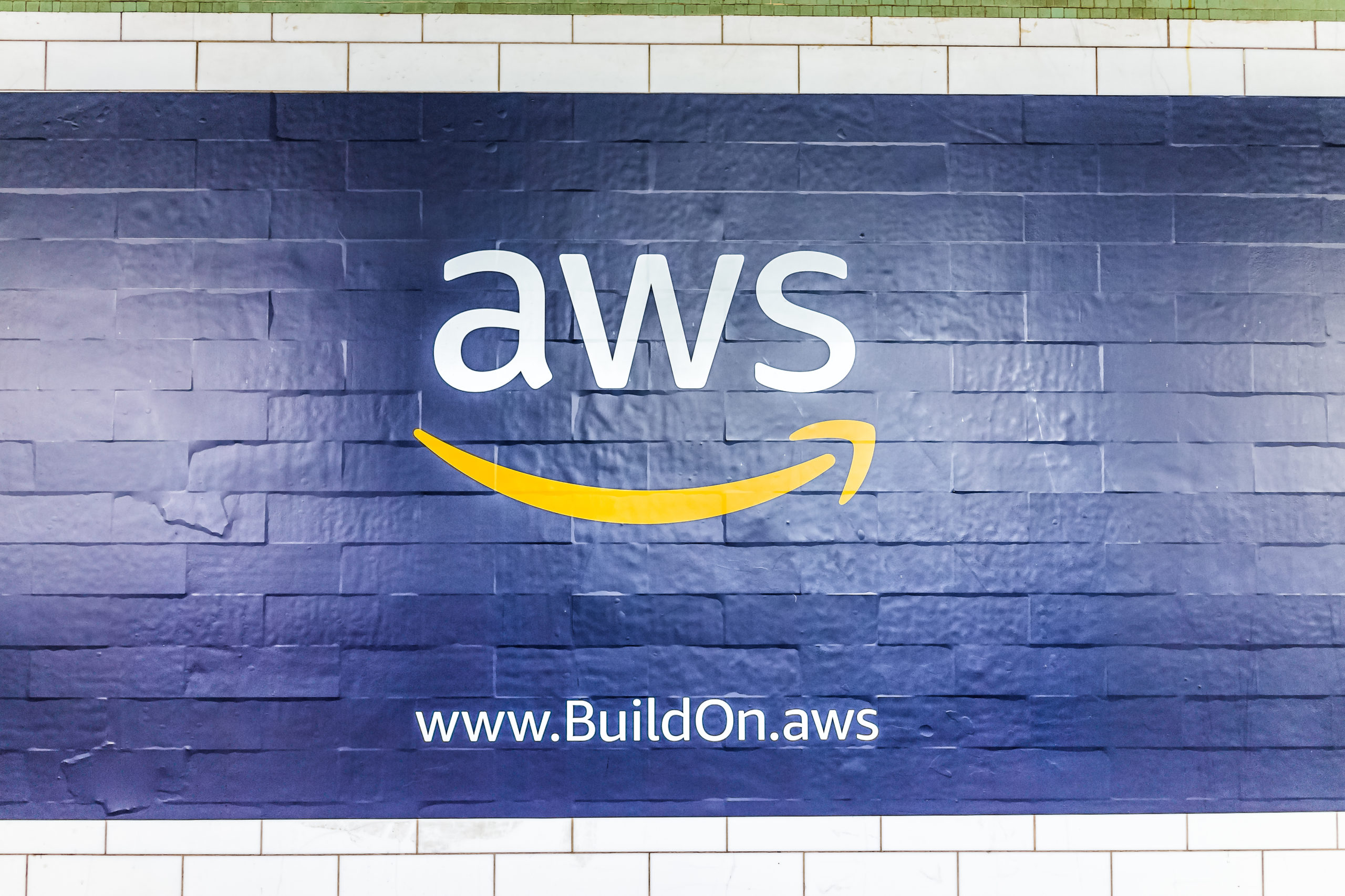 New York City, USA - October 30, 2017: Amazon Web Services AWS advertisement ad sign closeup in underground transit platform in NYC Subway Station, wall tiled, arrow